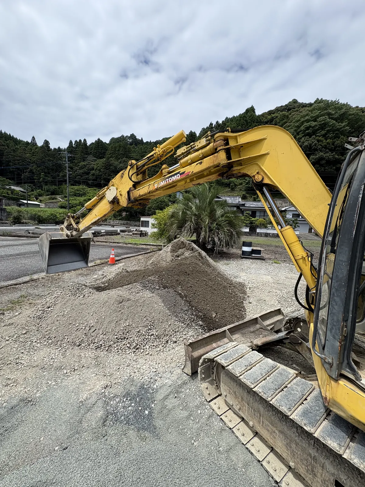 資材置き場のバックホウと砕石の山