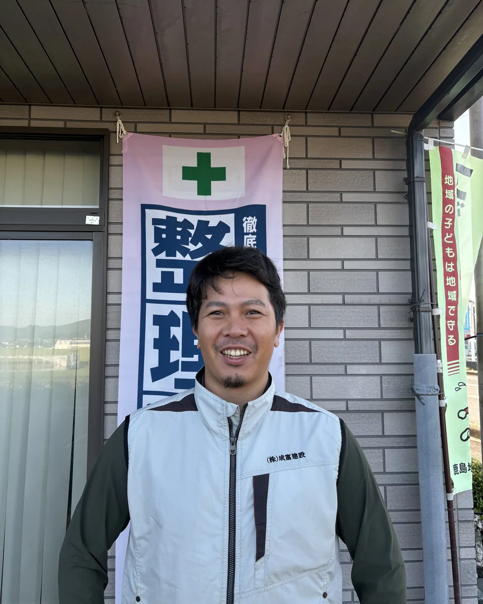 整理整頓の幟の前で笑顔を見せる成富建設の社員